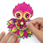 Para rąk trzyma i odkleja żywą, inspirowaną Hazelią, kwiatową naklejkę z kreskówki "Witraż na okno, zestaw do malowania z Hazelią" z jasnoróżowymi, żółtymi i zielonymi detalami na białym tle.