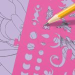 Używając "Szkicownika z Firiazem i Daliazem, kredkami, szablonami i naklejkami", żółta kredka kreśli półksiężyc na różowym szablonie nad skomplikowanym czarnym tuszem kotem i kwiatowym wzorem na lawendowym papierze pełnym geometrycznych i wirowych wycięć.