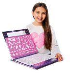 Uśmiechnięta dziewczyna o długich brązowych włosach siedzi przy stoliku, trzymając na tacy Szkicownik z Firiazem i Daliazem z kredkami, szablonami i naklejkami. Ma na sobie białą koszulę z różowym sercem.