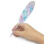 Dłoń trzyma Długopis z kolorowym piórkiem - Isadora Nebulous Stars, z niebieskim i różowym piórem z białymi wzorami płatków śniegu, błyszczącą srebrną końcówką i przezroczystym korpusem pióra, na gładkim białym tle.