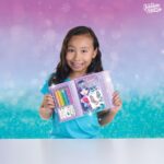 Uśmiechająca się dziewczynka ciemnoskóra trzymająca szkicownik z Isadroą do projektowania ubrań